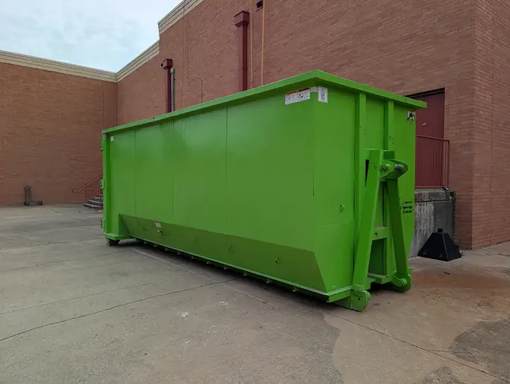 Roll-off dumpster beside a brick commercial building